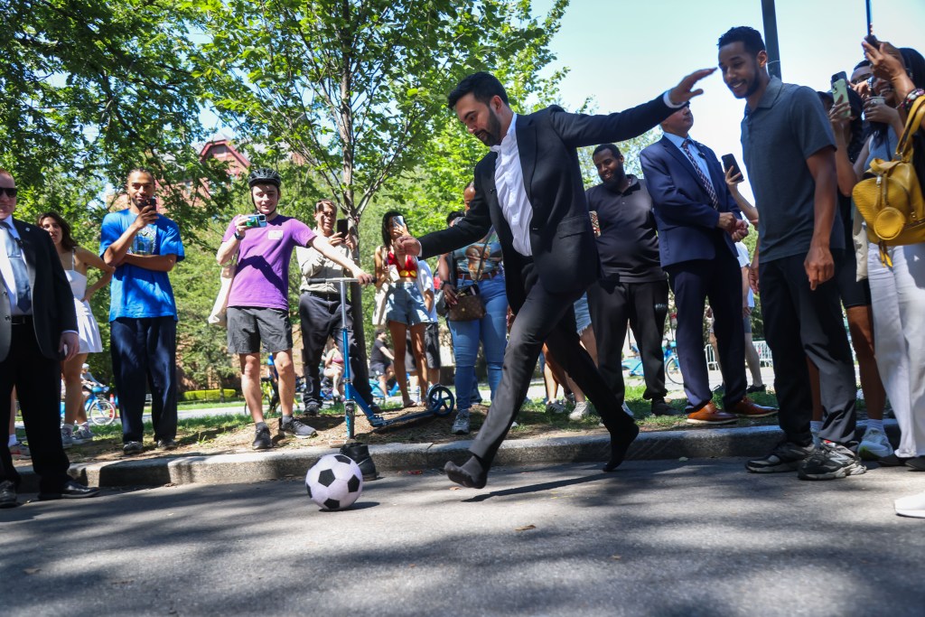 Zohran Mamdani kicking a soccer ball while campaigning in Brooklyn.