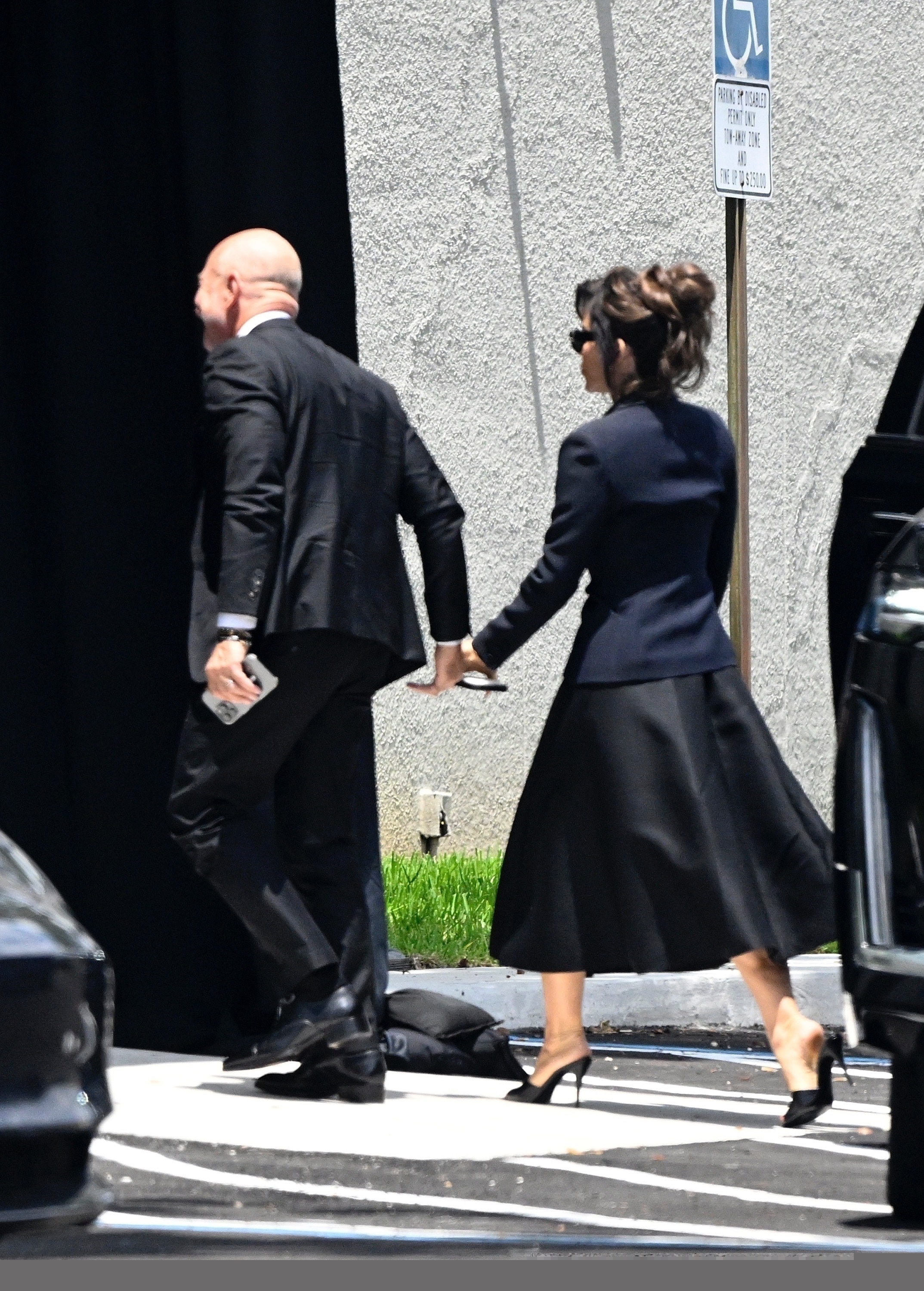 Lauren Sanchez and Jeff Bezos hold hands while wearing black. 