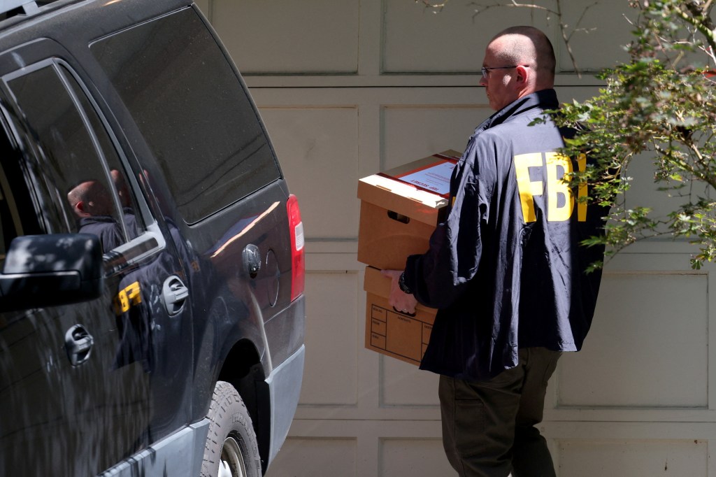 FBI agent carrying boxes from John Bolton's home.