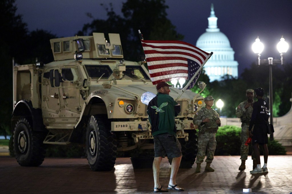 A protester waves a flag at National Guard members on the National Mall on Aug. 19, 2025.