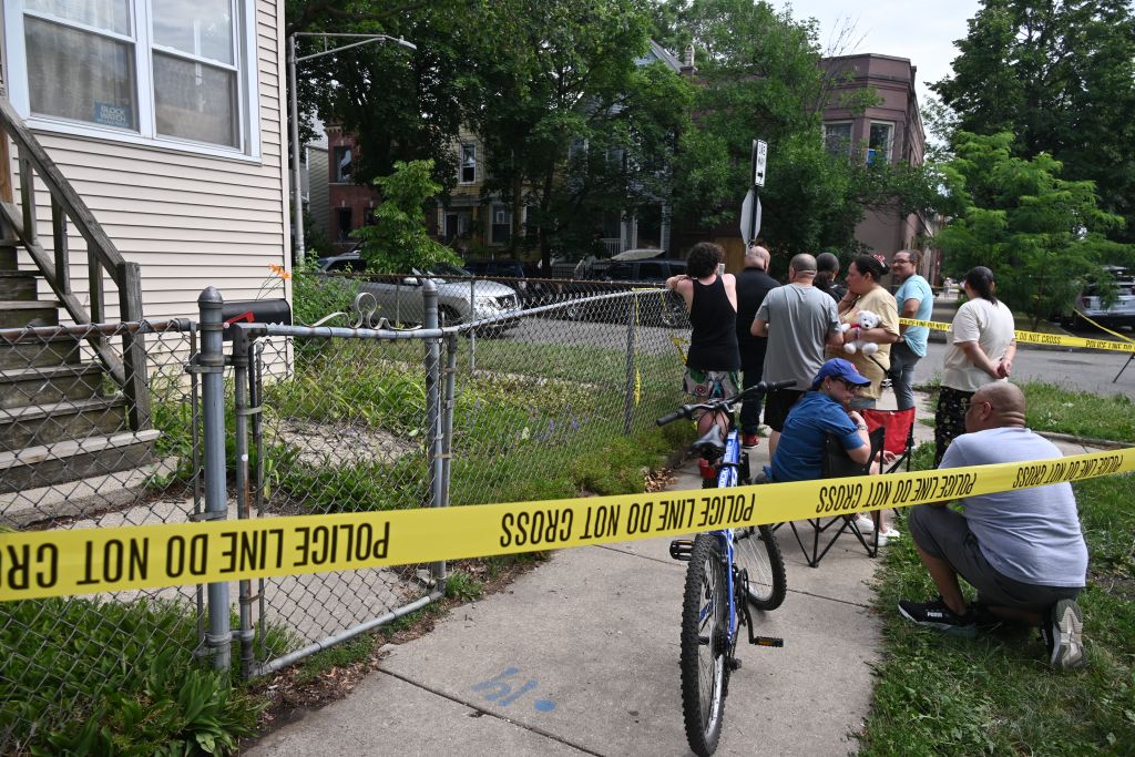 People stand behind police tape set up after one child as killed others injured in a stabbing and arson attack in Chicago, Ill. on July 4, 2025.
