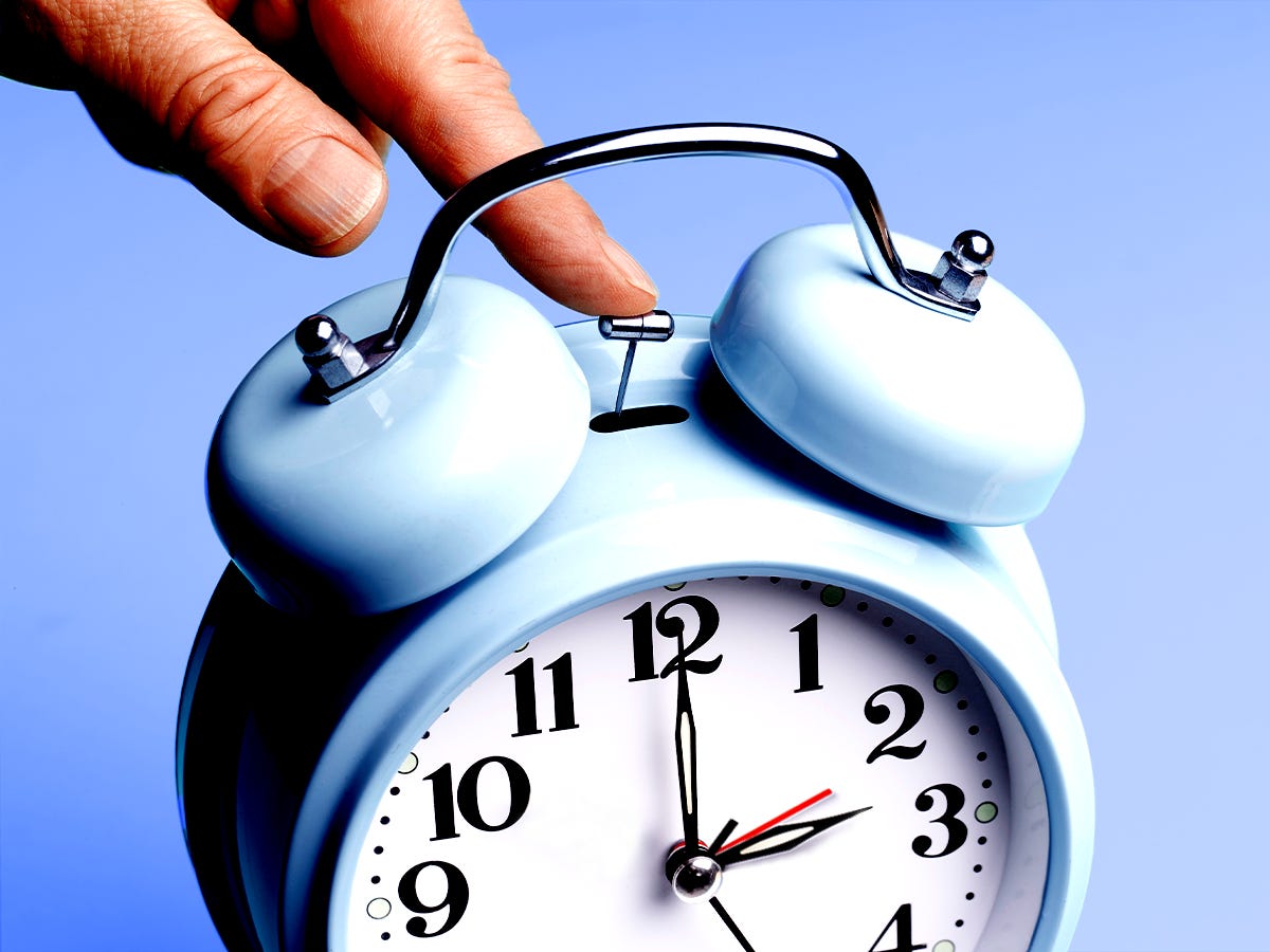 Hand stopping a blue alarm clock