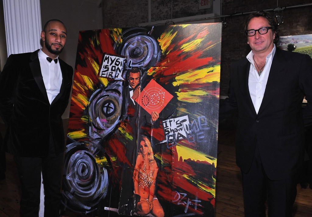Swizz Beatz and Phil Falcone standing beside a painting.