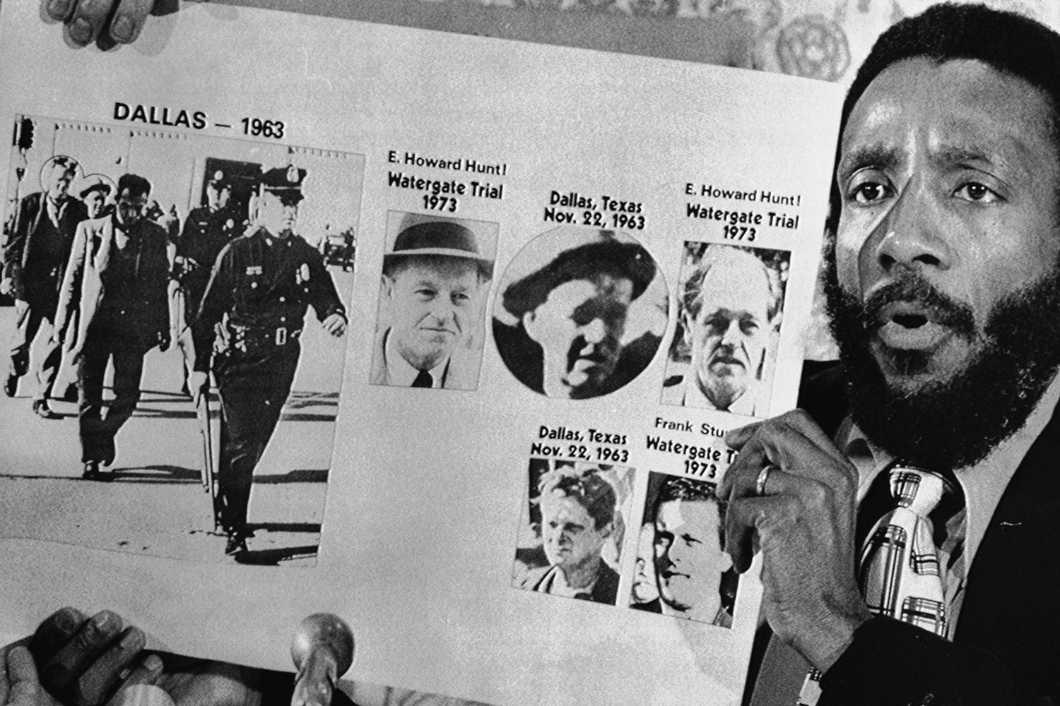 A man holds up photos to illustrate his conspiracy theory around the assassination of JFK.
