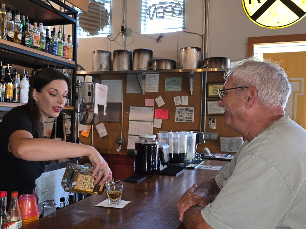 A bartender pouring a drink for a customer.