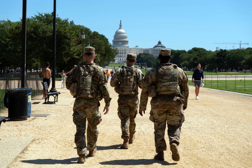 National Guard members patrolling the National Mall with the U.S. Capitol in the background.