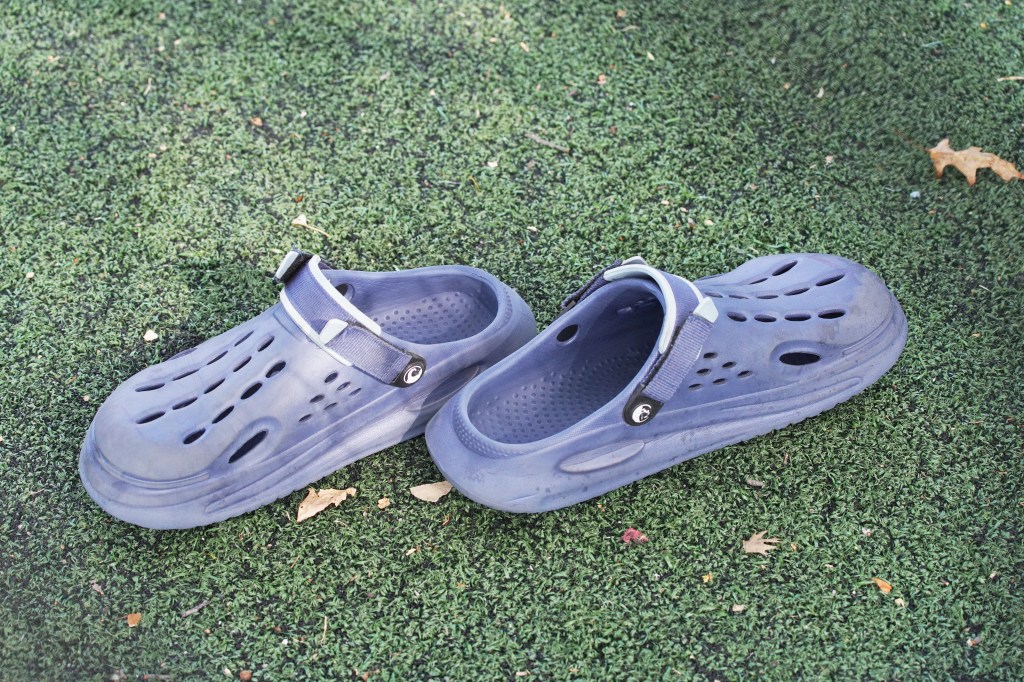 Pair of blue clogs left on the ground.