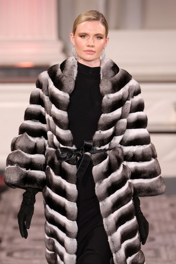 Model in a striped fur coat on a runway.