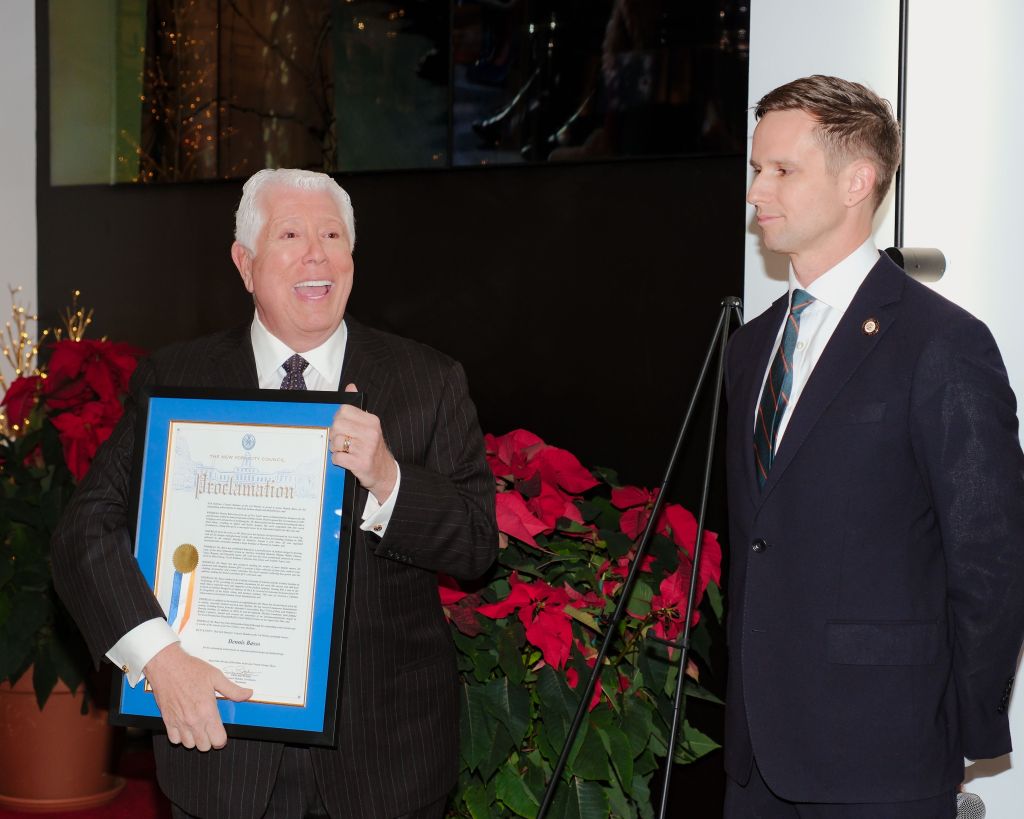Dennis Basso holding a proclamation with a man in a suit.