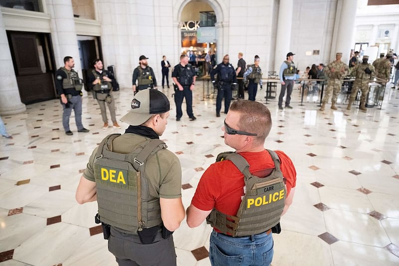 Law enforcement officials stand guard outside of Shake Shack while US Vice President JD Vance, Defense Secretary Pete Hegseth and White House Deputy Chief of Staff Stephen Miller (not pictured) visit with members of the National Guard stationed at Union Station in Washington, DC, on August 20, 2025. US President Donald Trump on August 11 deployed military and federal law enforcement to curb violent crime in Washington, as he seeks to make good on his campaign pledge to be a 