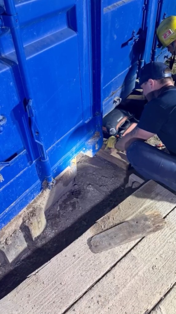 Workers securing a blue shipping container.