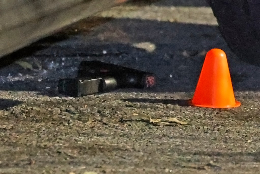 Gun and orange cone at a crime scene.