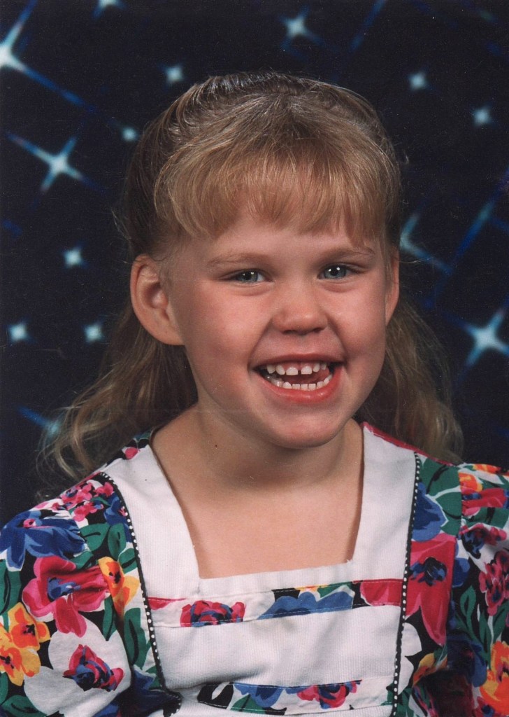 Portrait of a smiling young girl in a floral dress.