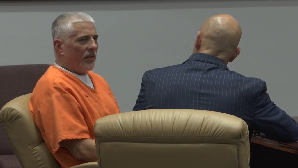 Defendant in orange jumpsuit and lawyer in court.