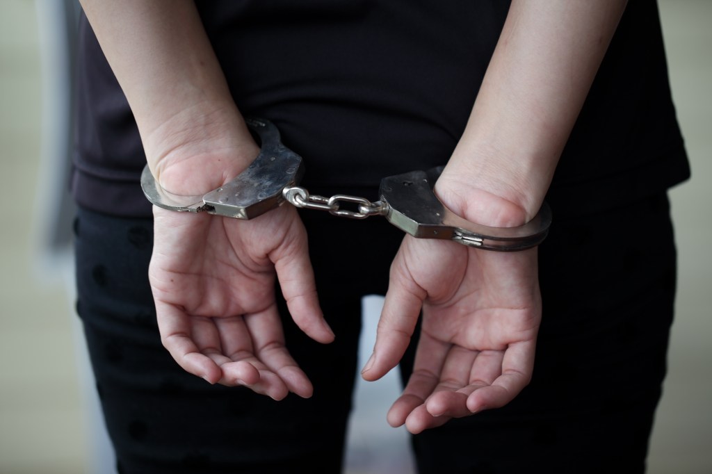 Person's hands cuffed behind their back.
