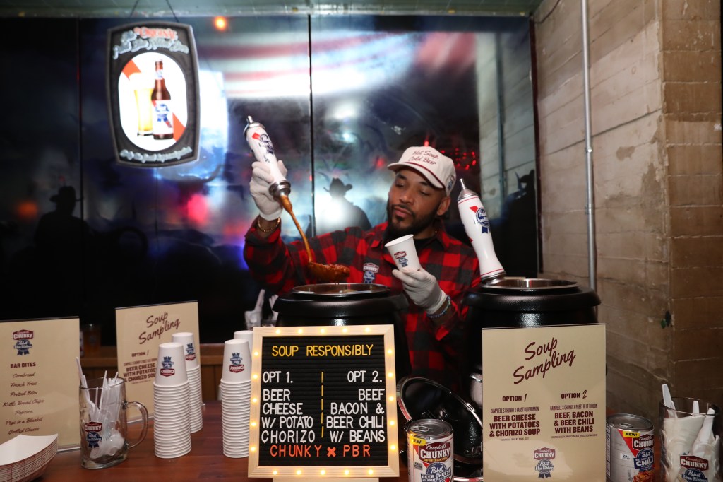 Person serving beer cheese and chorizo soup and beef, bacon, and beer chili soup.