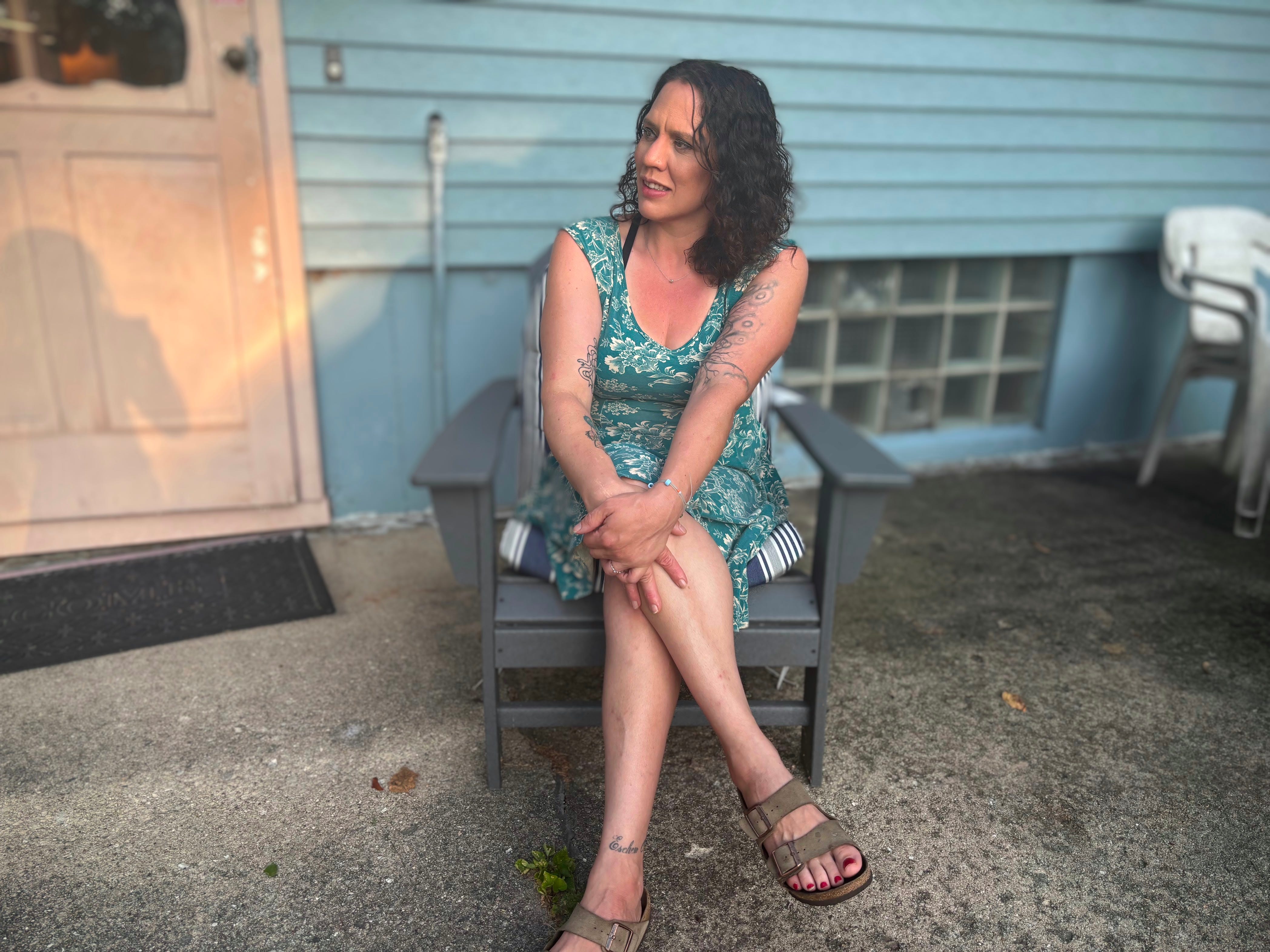 woman in green dress sitting in a chair looking away from the camera