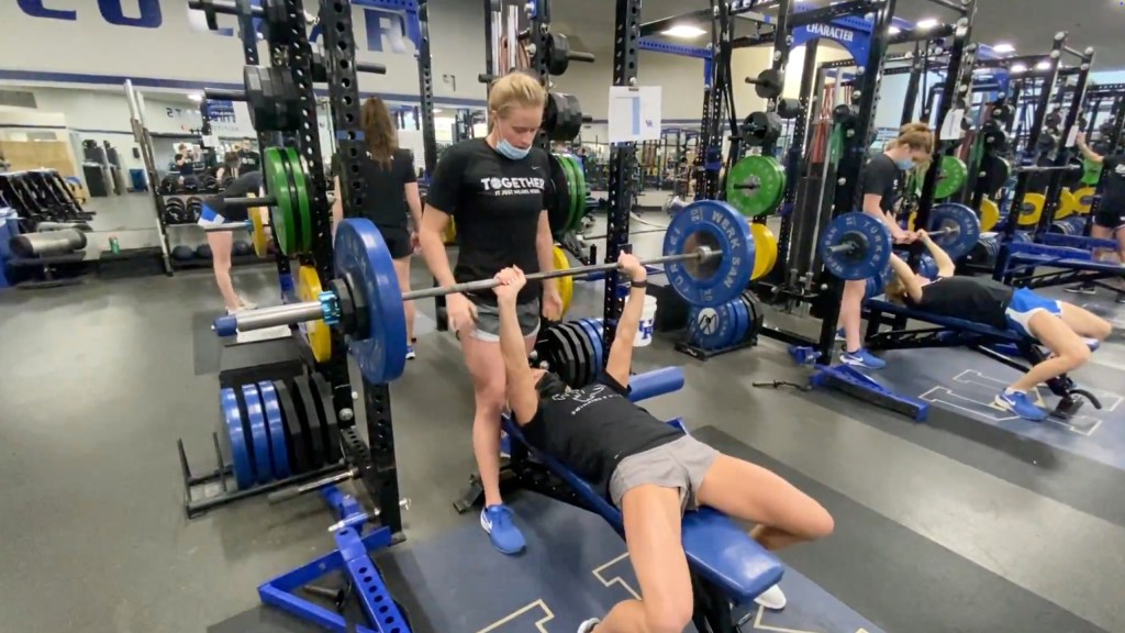 Woman bench pressing 165 lbs in a gym.
