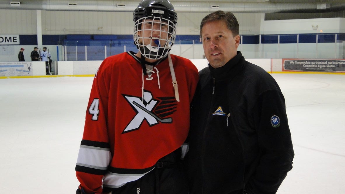 Dad posing with son in hockey gear