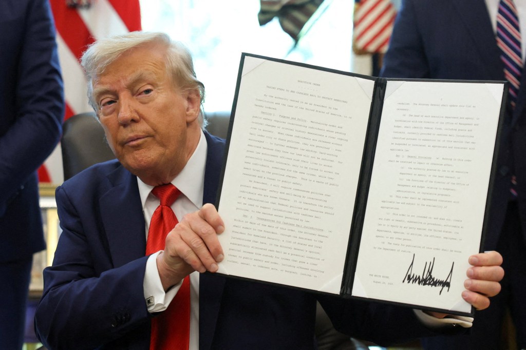 U.S. President Donald Trump holds up an executive order after signing it in the Oval Office at the White House in Washington, D.C., U.S., August 25, 2025. 