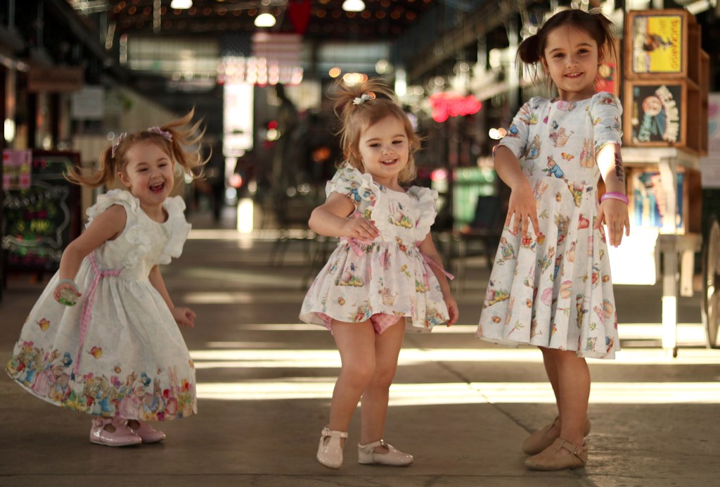Three young sisters in matching dresses.