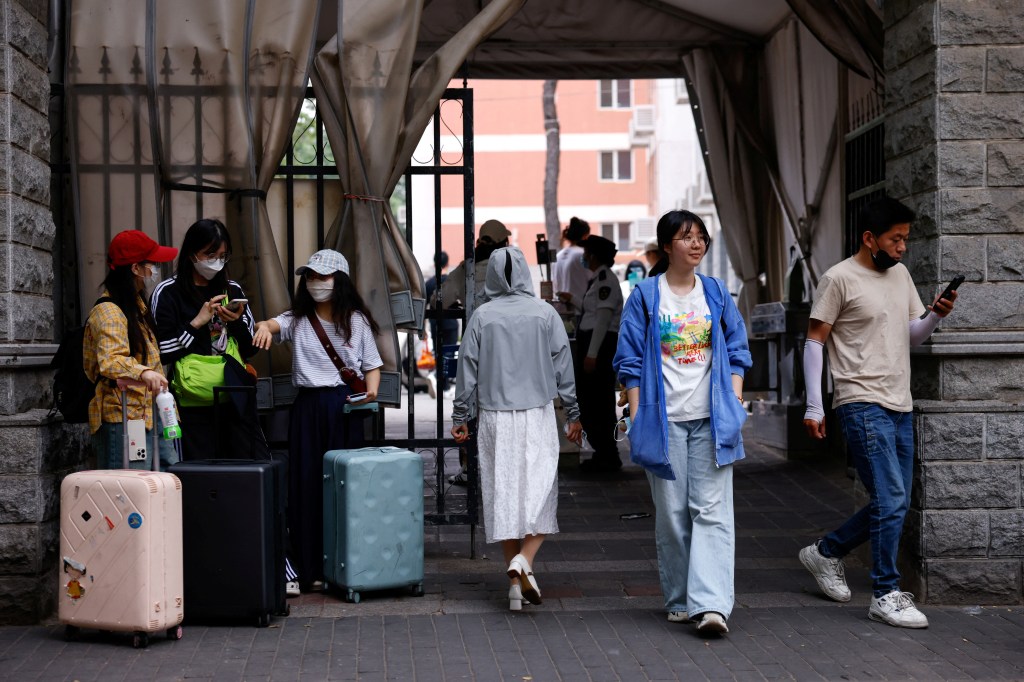 Chinese postgraduate students in Beijing with luggage, waiting to resume their U.S. visa process.