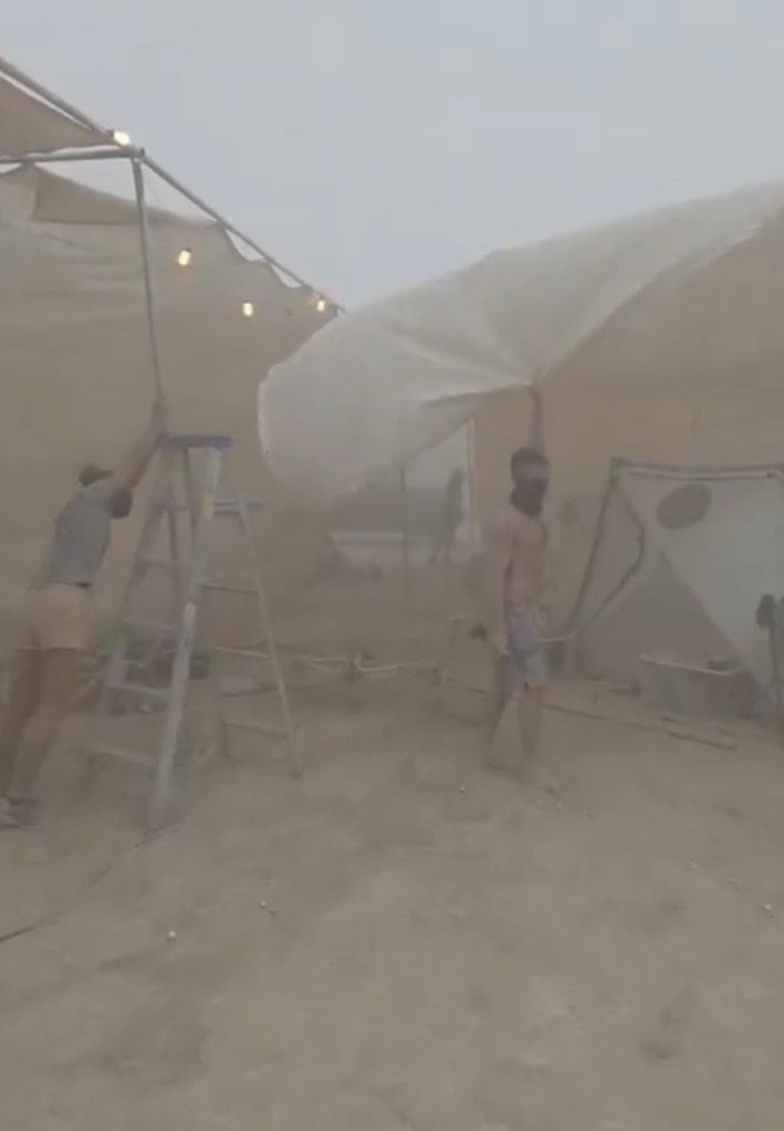 People securing a structure during a dust storm.