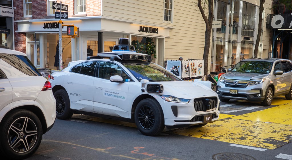 Self-driving Waymo car in city traffic.