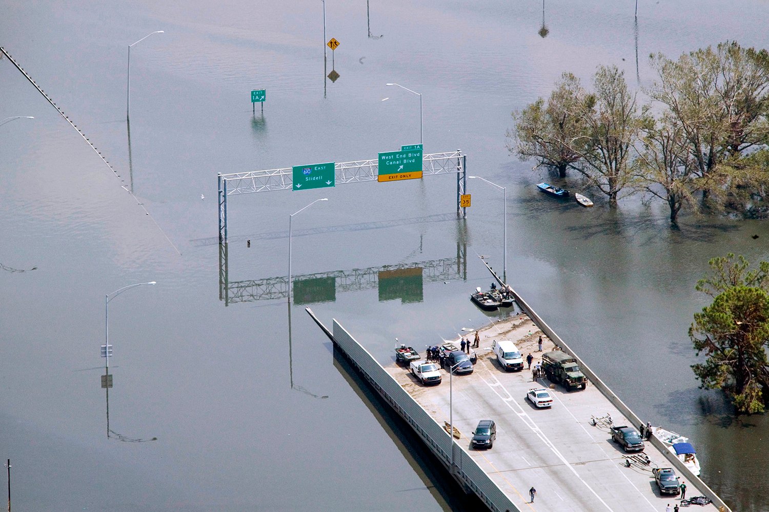 A highway with cars at its end is cut off by floodwaters.