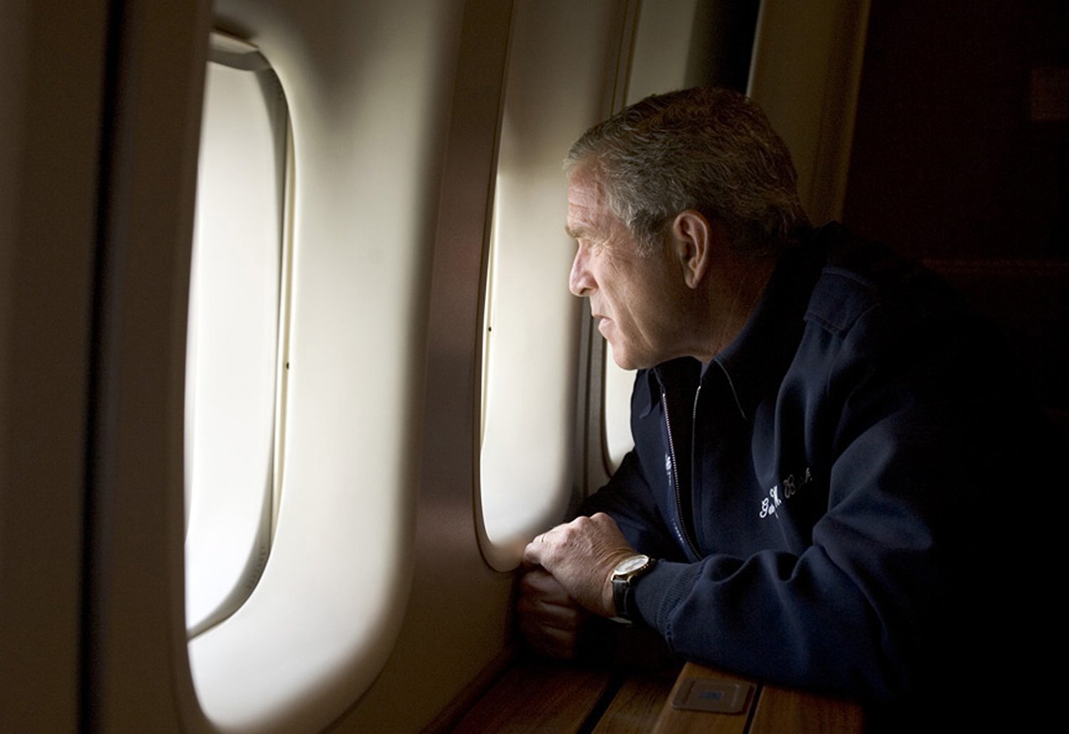 Bush leans his face toward the oval opening of a plane window.