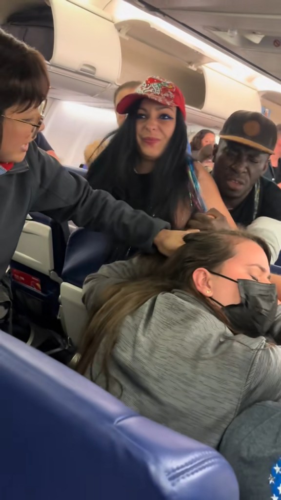 Perry is stopped by passengers as a flight attendant attempts to help Rombola during the attack.