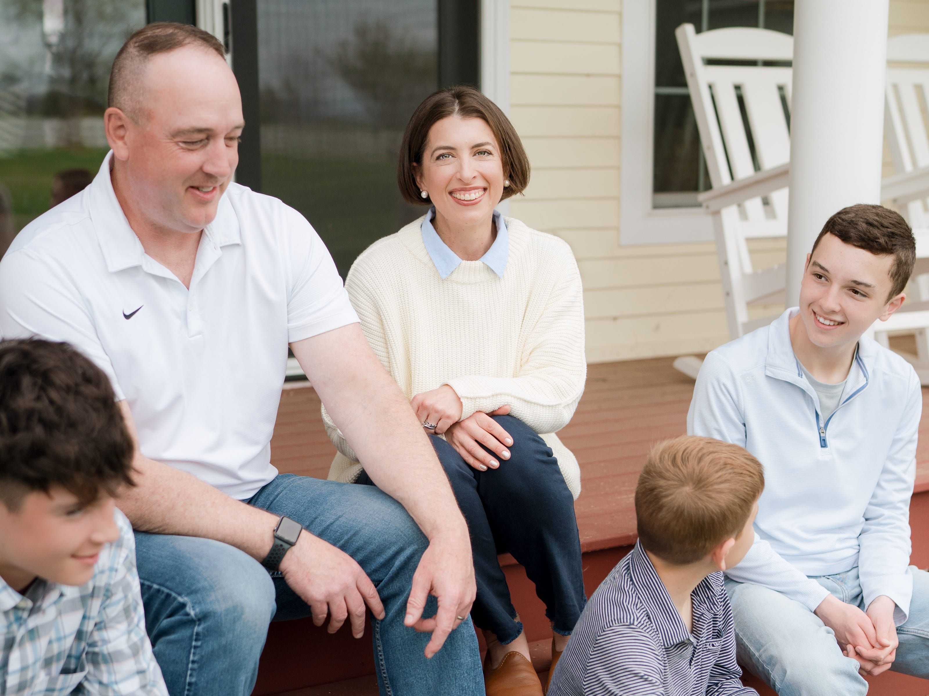Blair Lonergan and her family sitting on the porch of their home.