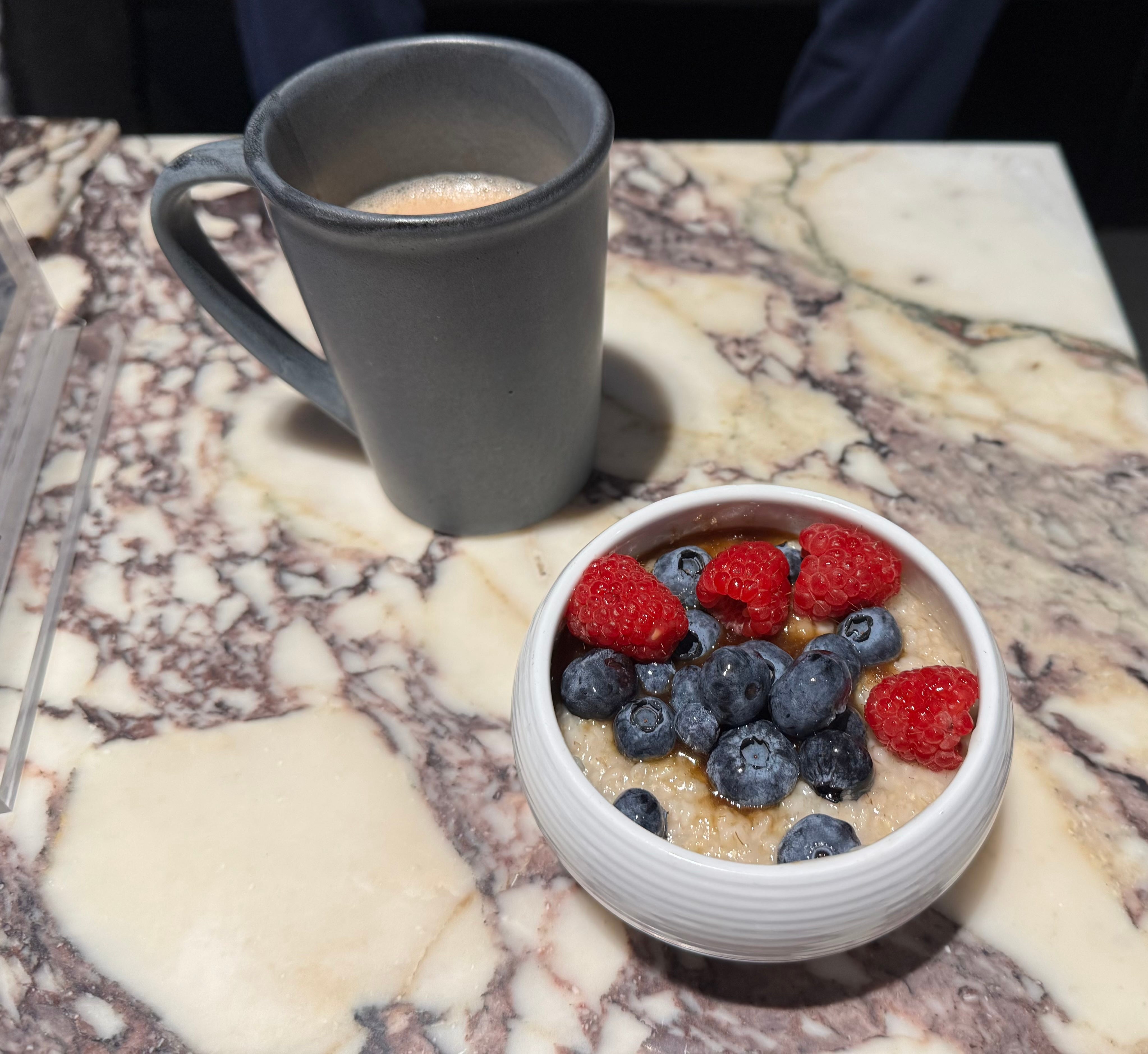 A cup of coffee and a bowl of oatmeal with berries.