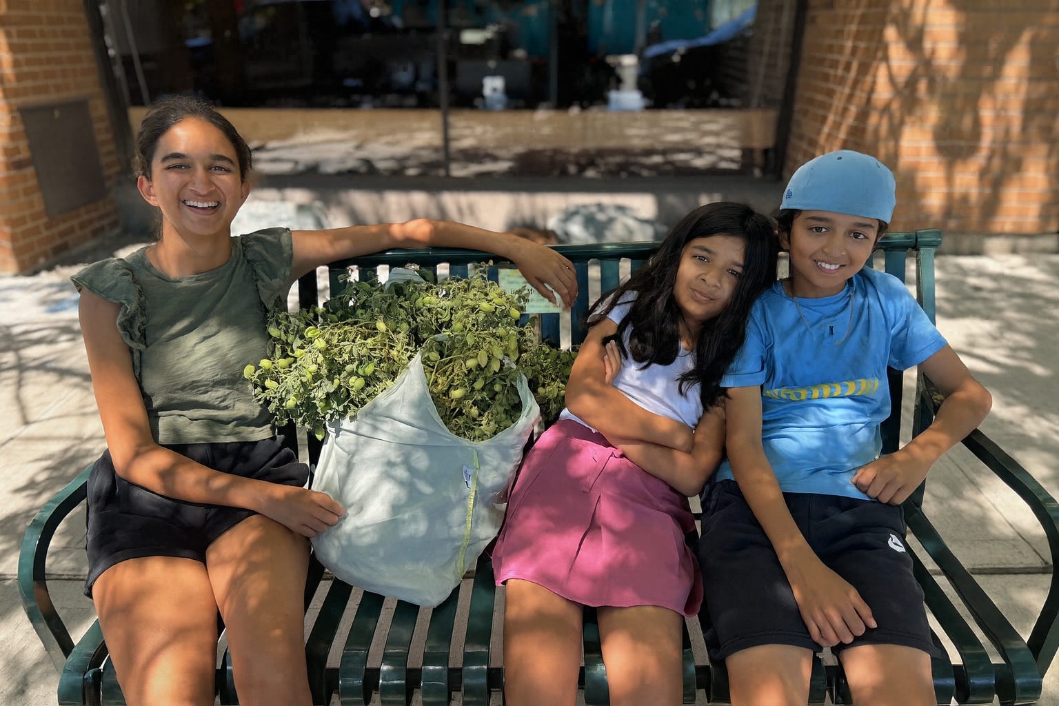 A mom and her two kids sit on a bench.