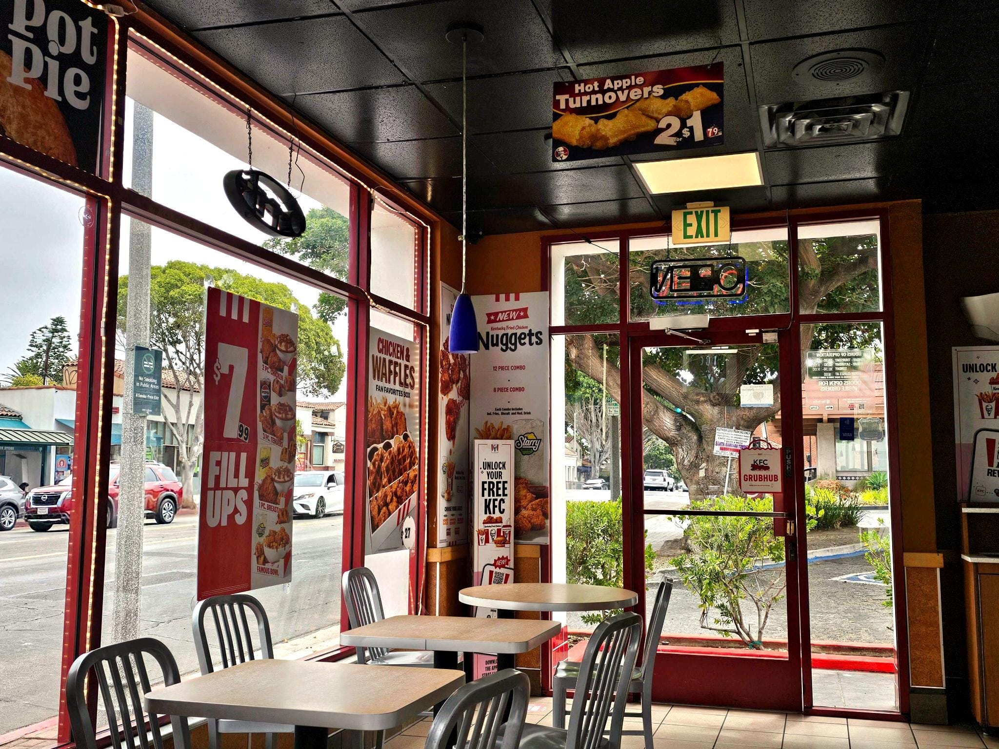 The inside of a KFC store shows signage and empty tables.
