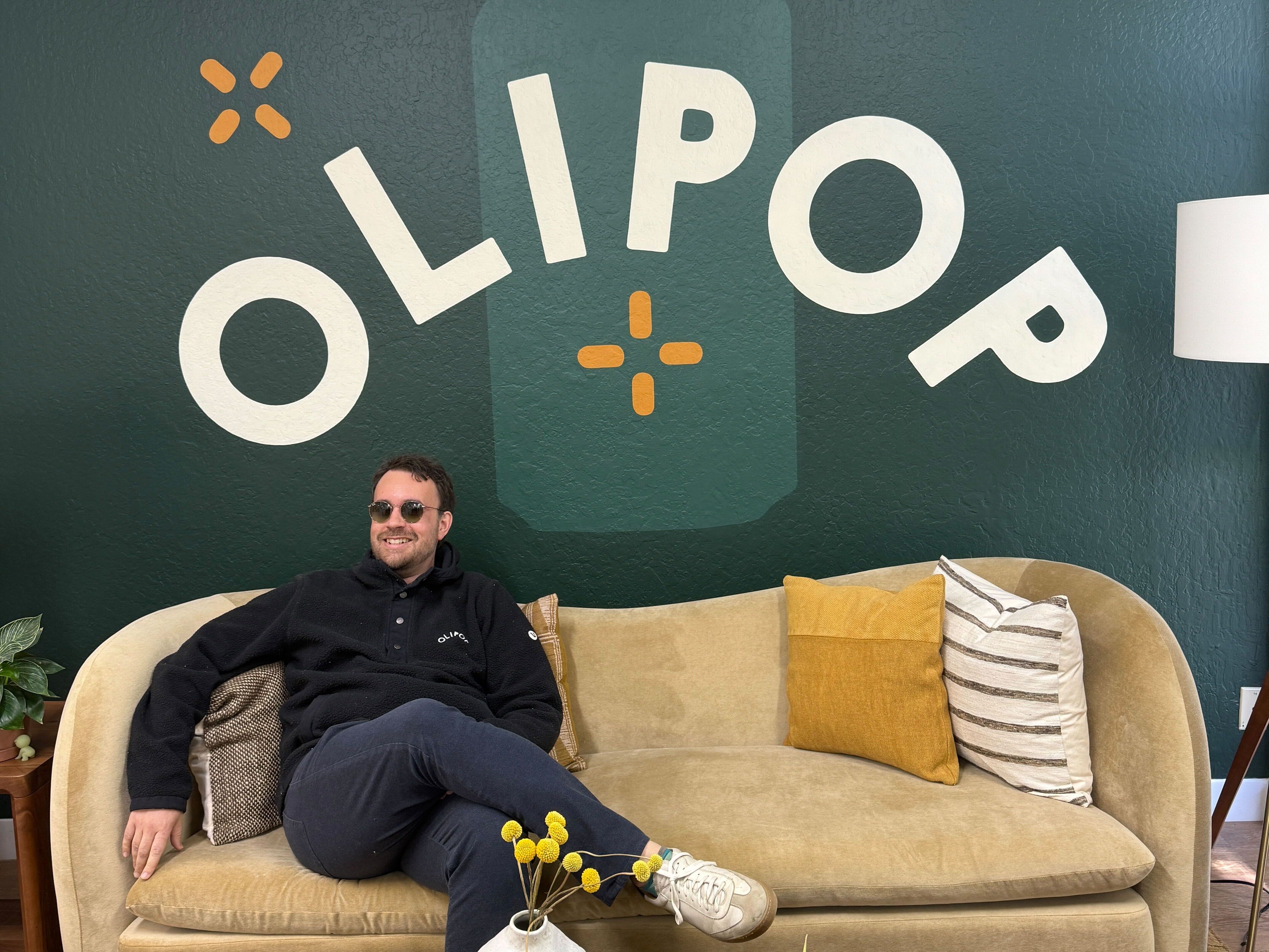 Ben Goodwin sitting on couch withn Olipop wall behind him