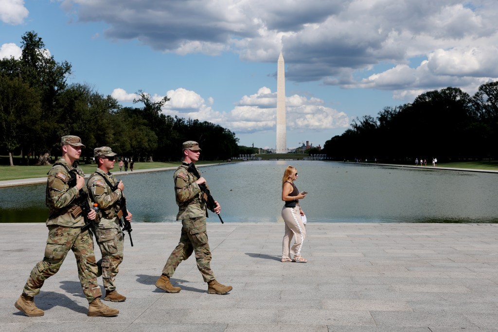 National Guard soldiers patrolling the National Mall in Washington, D.C., with the Washington Monument in the background.