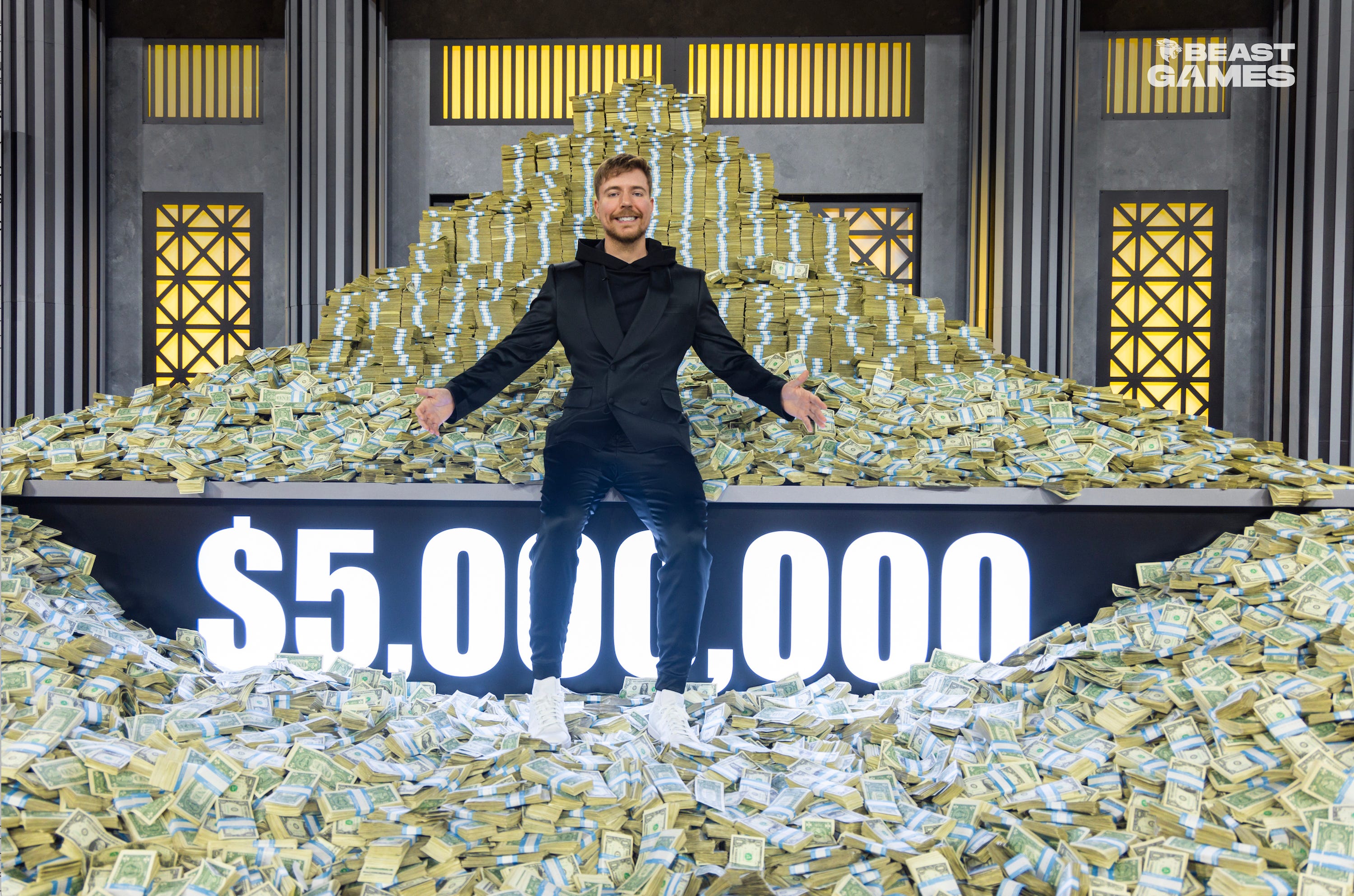 YouTuber MrBeast stands surrounded by piles of money in a promotional photo for his reality competition show "Beast Games."