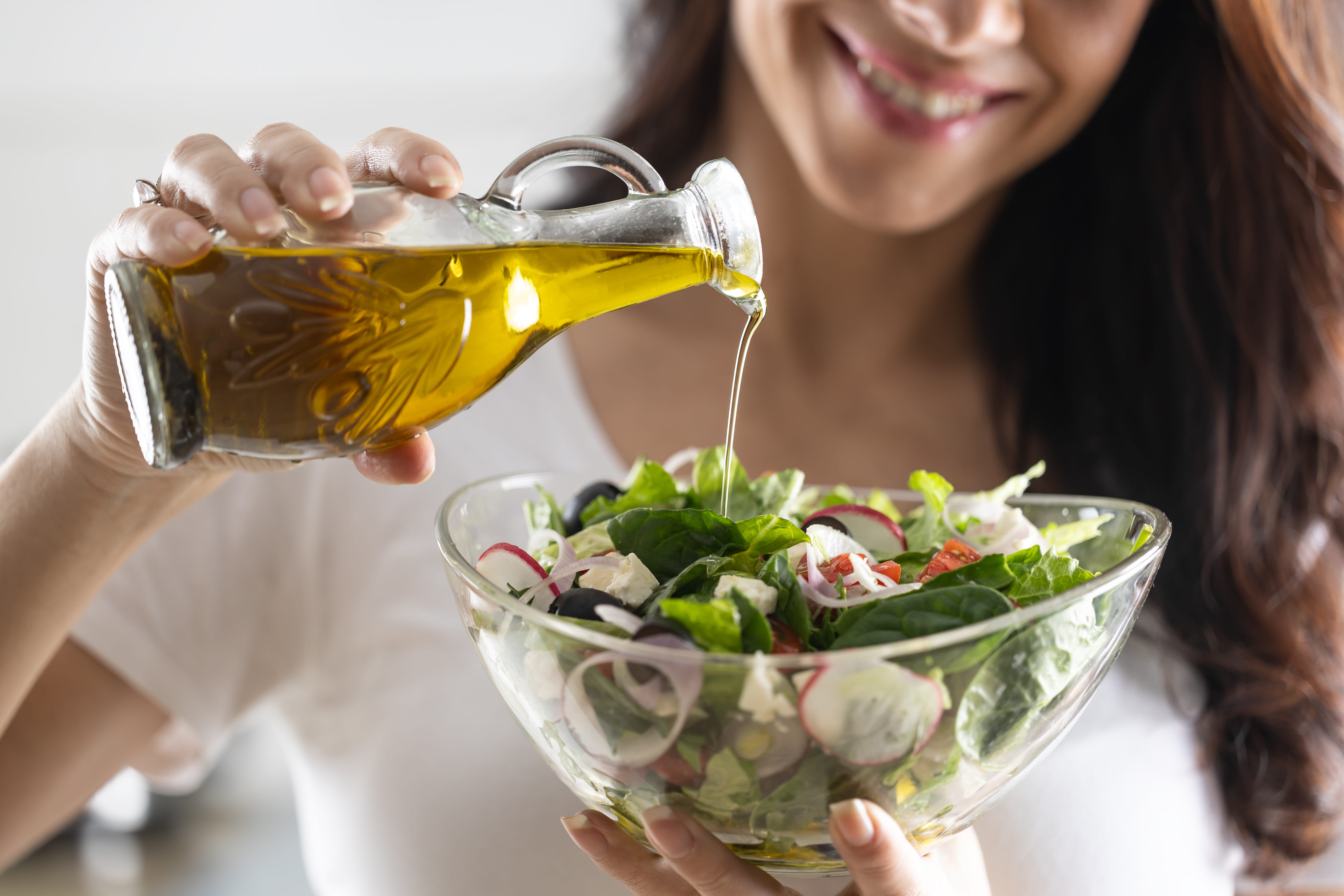 drizzling olive oil over salad