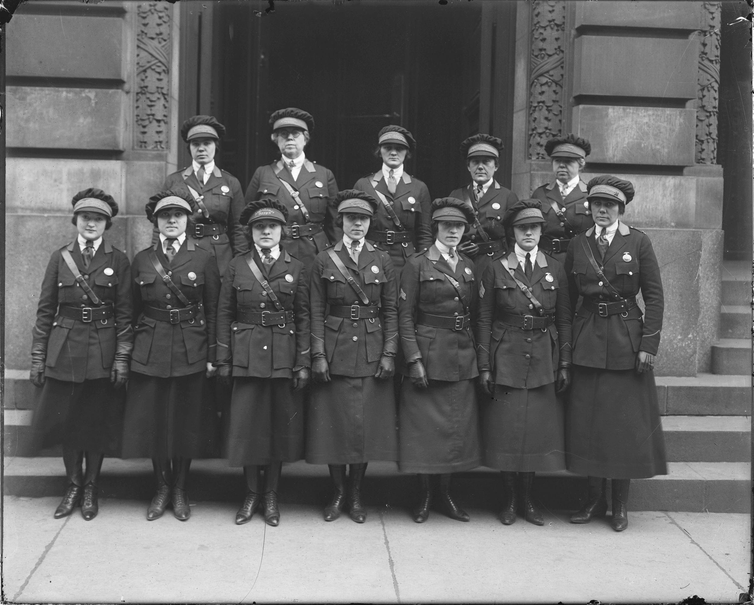 12 policewomen in uniform are posing outside a building for the photograph.