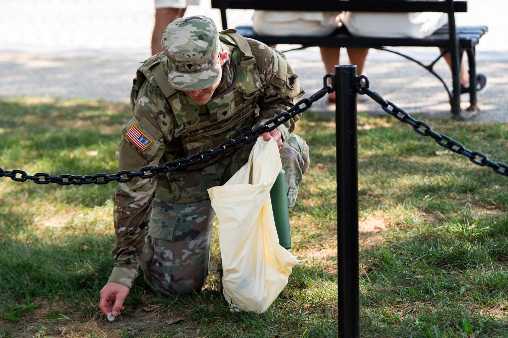 A National Guard soldier picking up trash.