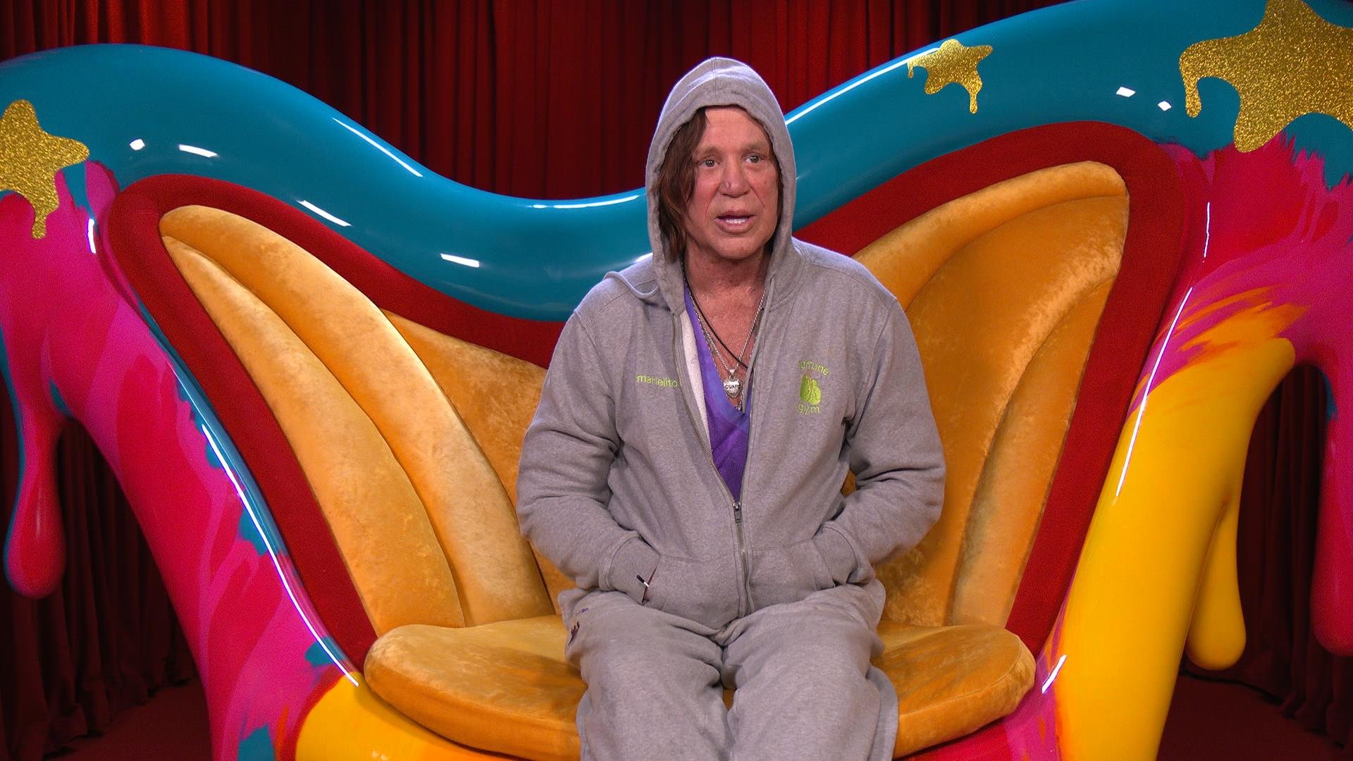 Mickey Rourke sits in a colorful chair. 