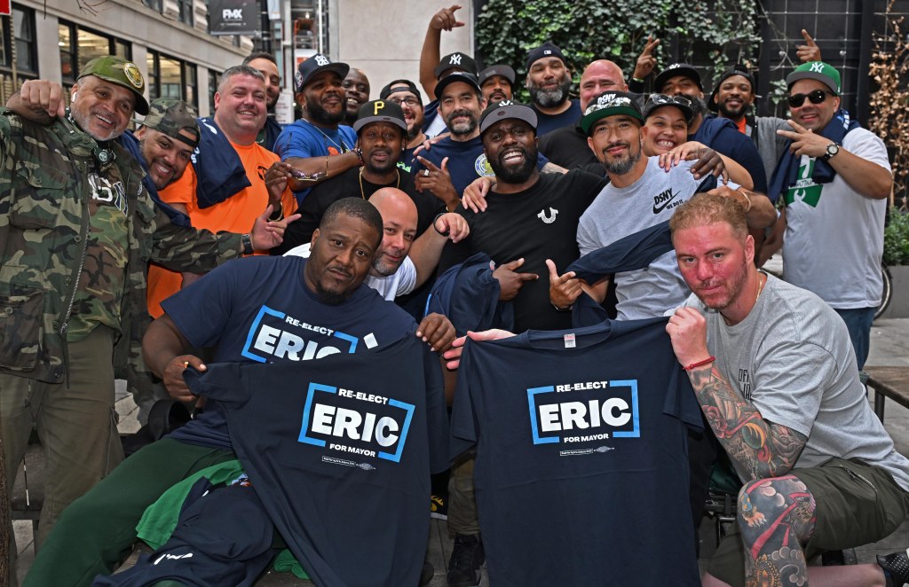 NYC sanitation workers holding shirts supporting Mayor Adams.