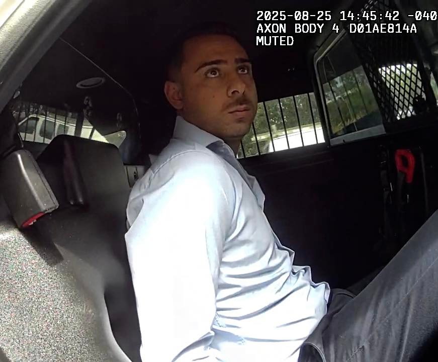 Man in handcuffs sitting in the back of a police car.