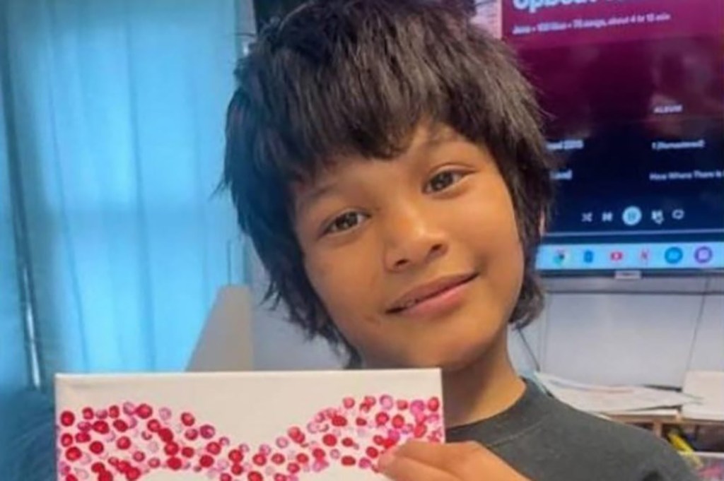 Photo of Bryan Vasquez, a 12-year-old boy, holding a painting.
