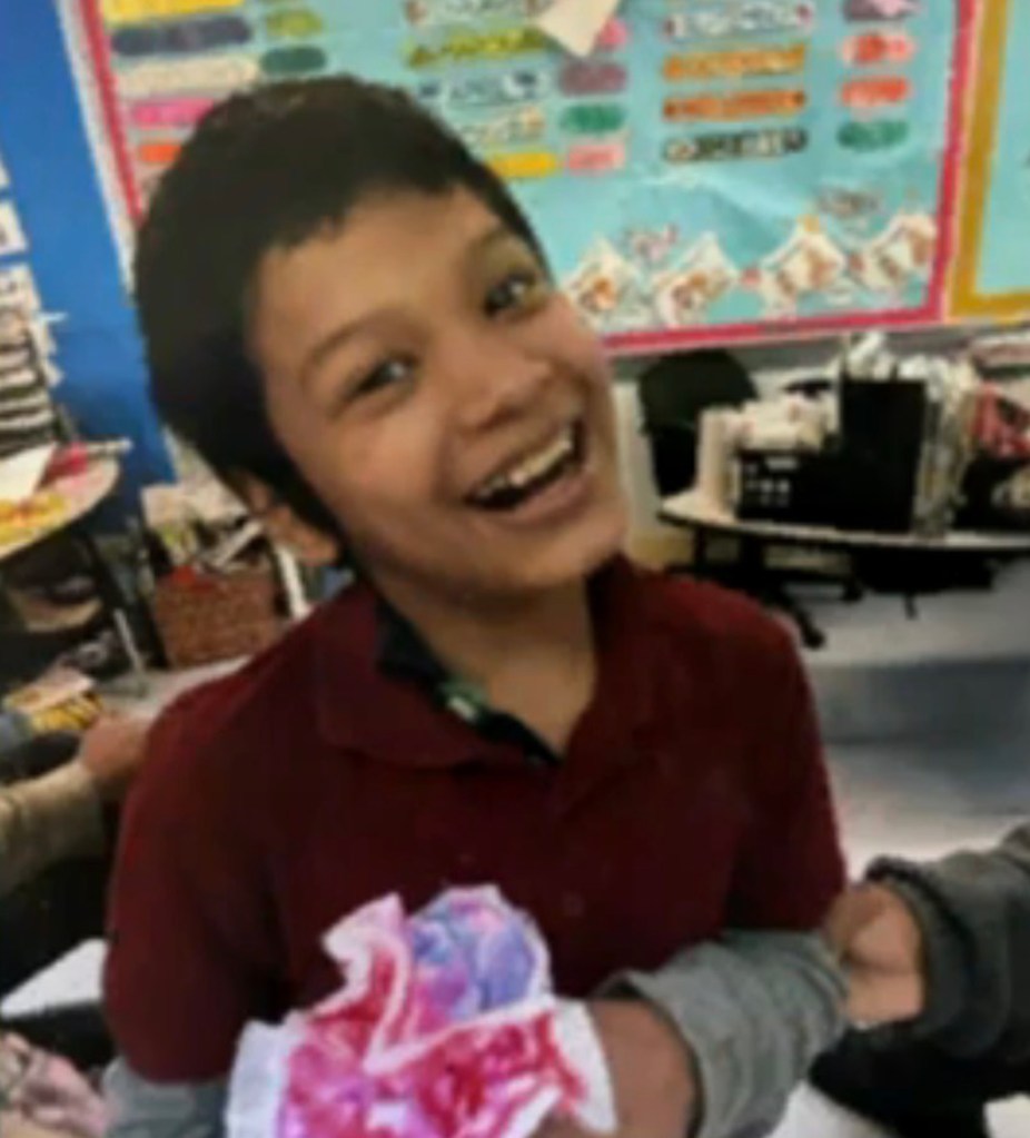 Photo of a smiling boy holding a craft project.