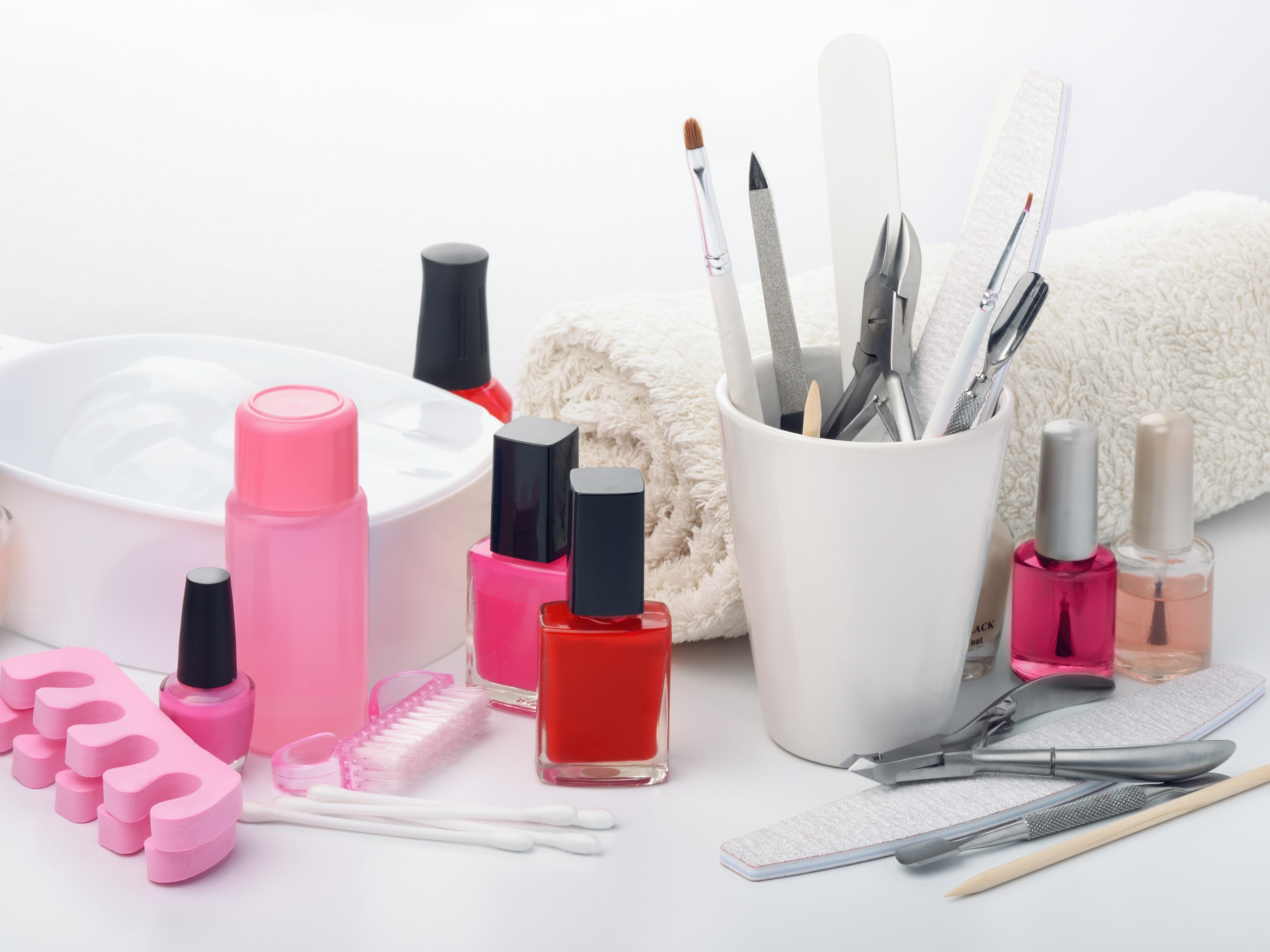 Manicure equipment, including nail polish and nail shaping tools, on a white table.