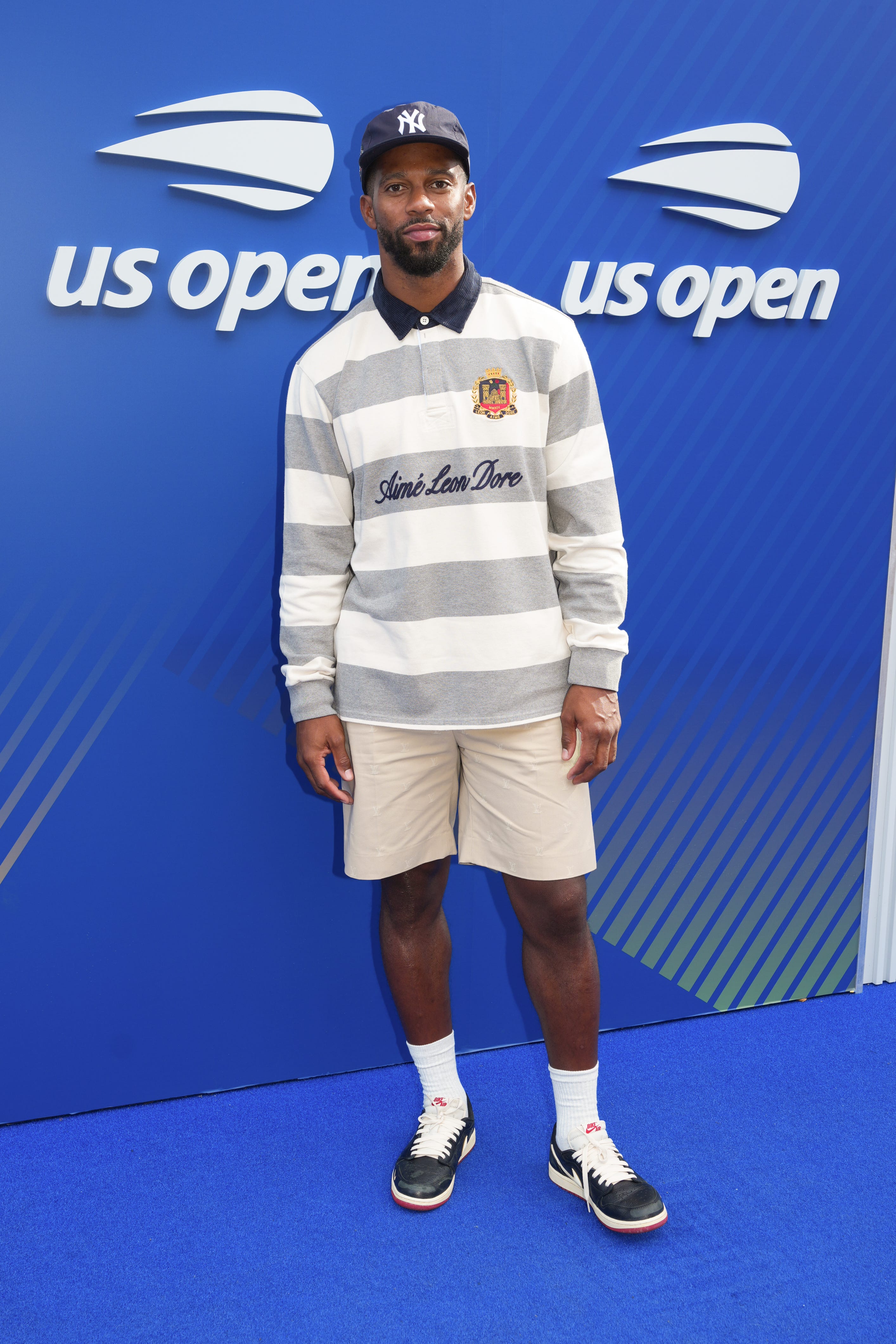 Victor Cruz wears a striped shirt and khaki shorts at the US Open.