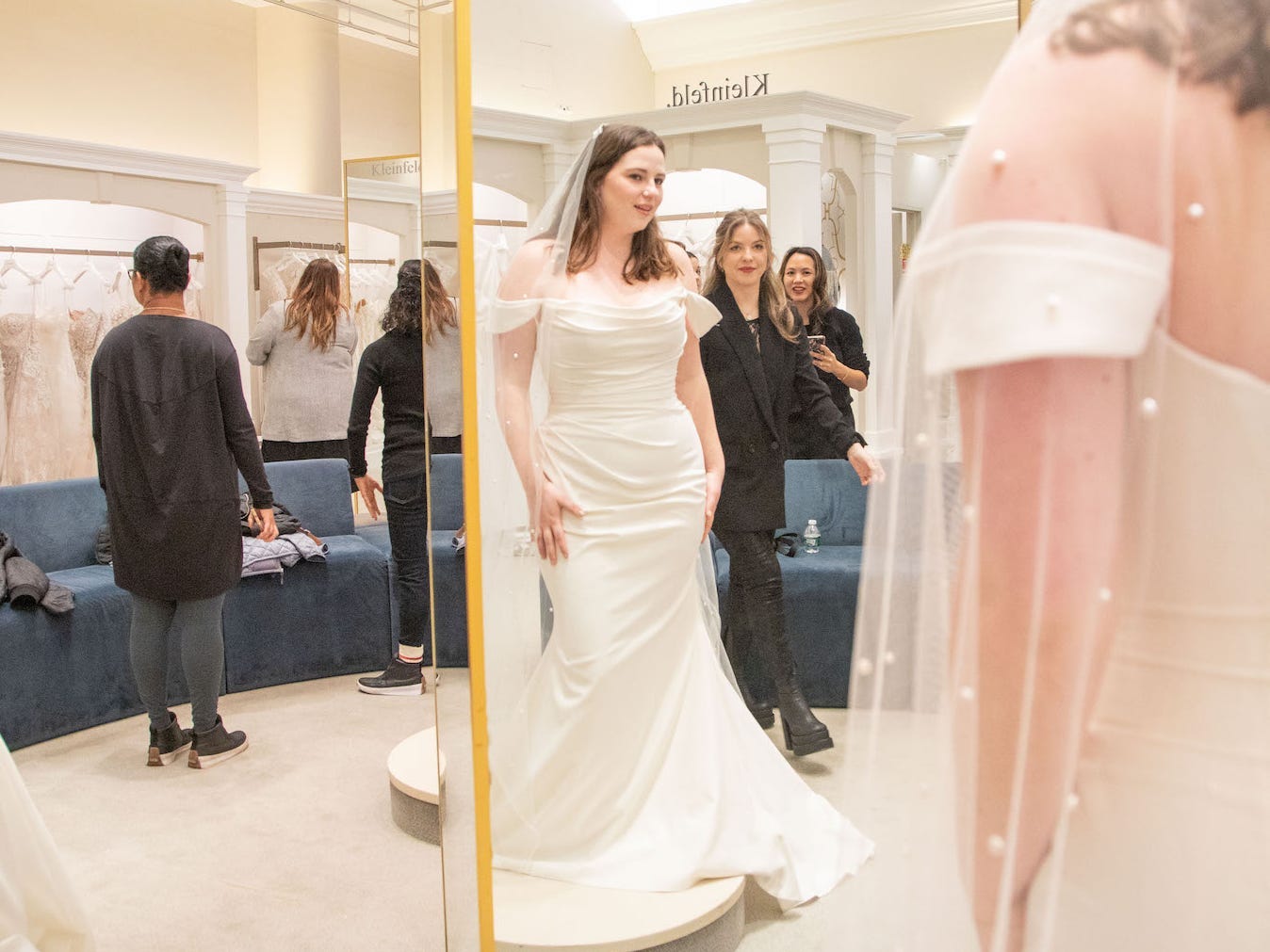 A woman in a wedding dress looks at herself in a mirror.