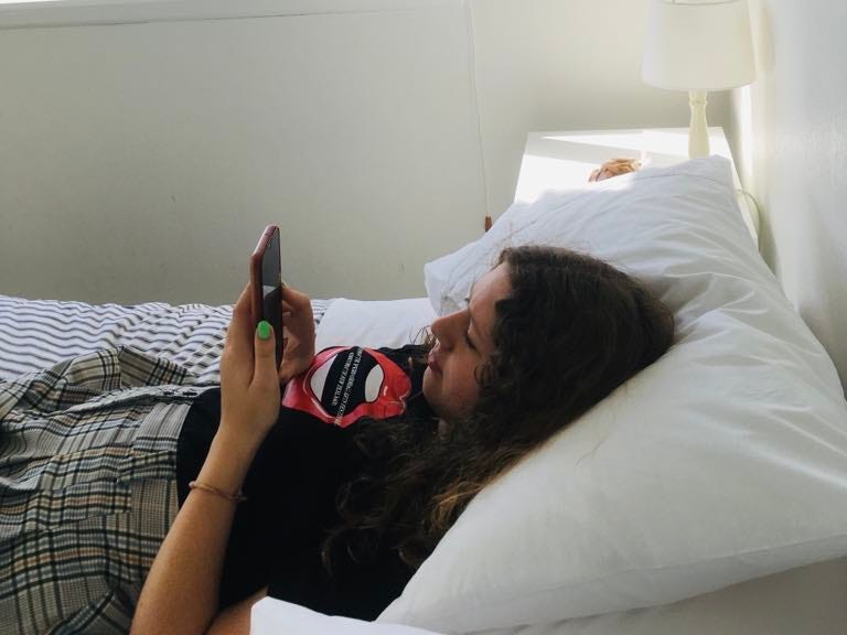Teen looking at phone in bed